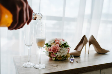 Pouring champagne in glasses standing on table. Wedding day.