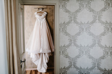 Wedding dress hanging against a wall background in the room.