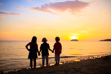 Child playing on ocean beach. Kid at sunset sea.