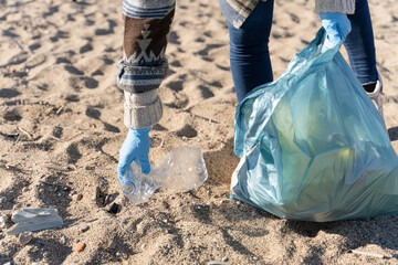 Hand of volunteer person collecting plastic bottle trash on the beach. Working for Ecology 