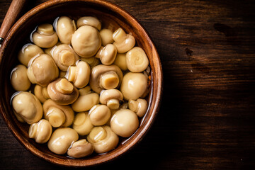 Wooden bowl with small pickled mushrooms. 