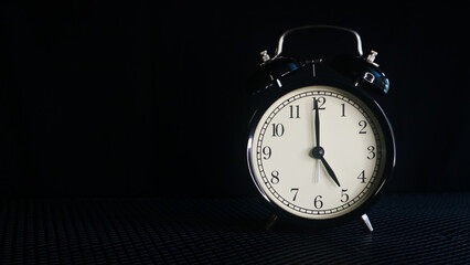 Background photo of an alarm clock showing 5:00