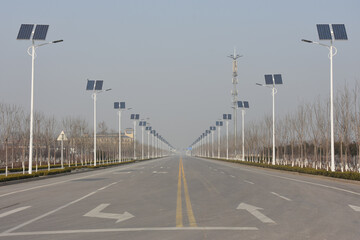 Breite, leere, ewig lange Straße in China mit solarbetriebenen Straßenlaternen und Smog