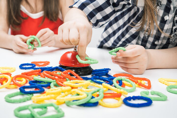 Cropped photo of group of girls children playing board game ring near bell, joining buckling geometric figures in chain.