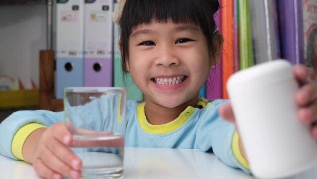 Cute little girl eating alpha omega 3 or Vitamin pill. Vitamin supplements for children for better immunity.