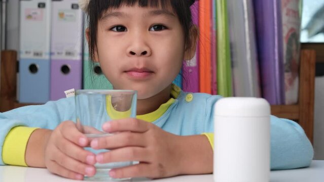 Cute little girl eating alpha omega 3 or Vitamin pill. Vitamin supplements for children for better immunity.