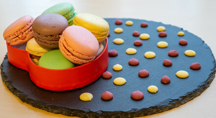 Macaroons in a red heart box and chocolate flakes on a slate plate