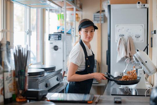 Portrait woman chef baking pancakes in an apron uniform. Fast food service of the city. fast food restaurant is a small business.