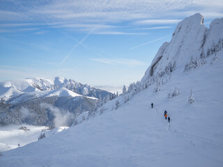 Mountain hikers on a path in snow to moutain summit, in a bright sunny winter day. Winter outdoor...