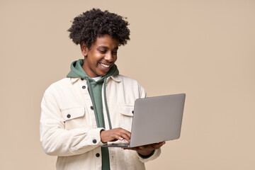 Happy smiling African American teenager student holding laptop using computer technology presenting...
