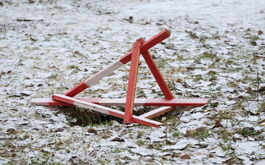 The sinkhole in the snow-covered ground is covered with a red wooden barrier