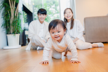 ハイハイをする赤ちゃんと子供の成長を見守る両親