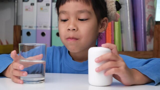 Cute little girl eating alpha omega 3 or Vitamin pill. Vitamin supplements for children for better immunity.