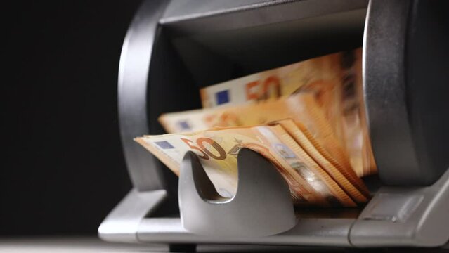 Close up of euro banknotes while being counted. Money counting equipment for paper money calculation. Automatic mechanism for bank financial operations. Paper currency detector