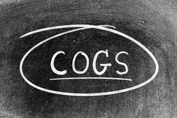White chalk hand writing in word COGS (Abbreviation of Cost of goods sold) and circle shape on...