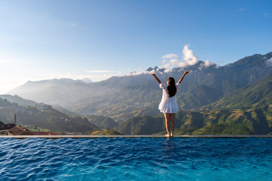 Young woman traveler relaxing at sky pool and looking at the beautiful nature landscape with blue sky and mountains in Sapa, Vietnam