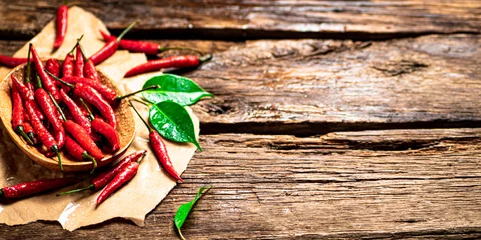 Fotobehang Hot chili peppers with leaves on a plate. © Artem Shadrin