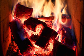 fire burns in the fireplace. Fireplace with flame fire ashes. burning billets in hot brick stove
