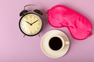 Sleeping mask, alarm clock and fragrant coffee on a lilac background. FLAT LAY. Concept of rest and...