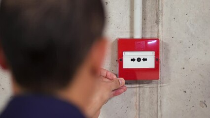 A back view of electrician installing fire alarm system at factory