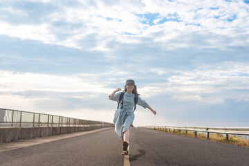 Happy smile young woman traveller with backpack walking on road travel on summer holiday