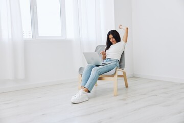 Woman relaxing at home and sipping her hands sitting in a chair with her laptop, lifestyle homemade spirits. Mockup, free copy space