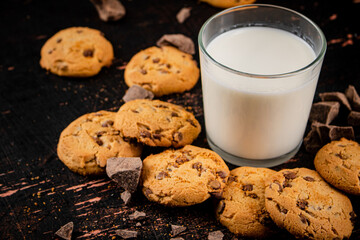 Homemade cookies with pieces of milk chocolate and a glass of milk. 