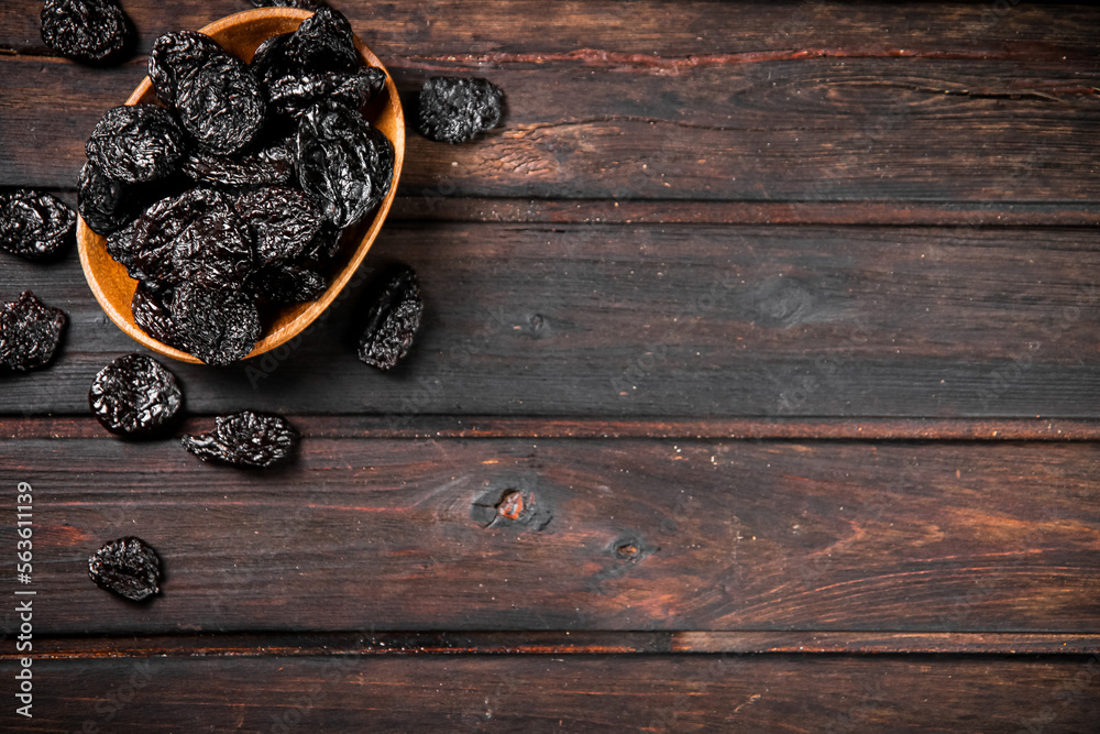 Poster Prunes in a plate on a wooden background.