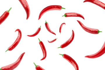 Falling red hot chilli peppers isolated on white background, selective focus