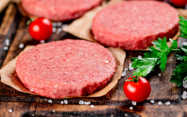 Raw burger on a cutting board with parsley and salt. 