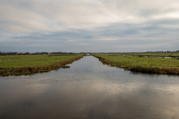 Typical Dutch rural scenery showing the flat Netherlands. canal water is part of a flood management system for the polder which is land reclaimed from the sea and converted into arable farm fields