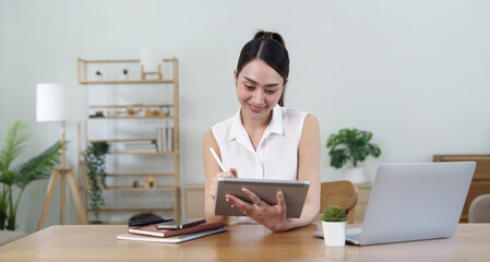 Young woman working on a laptop in the office. Asian businesswoman sitting at her workplace in the office. Beautiful Freelancer Woman working online at her home.