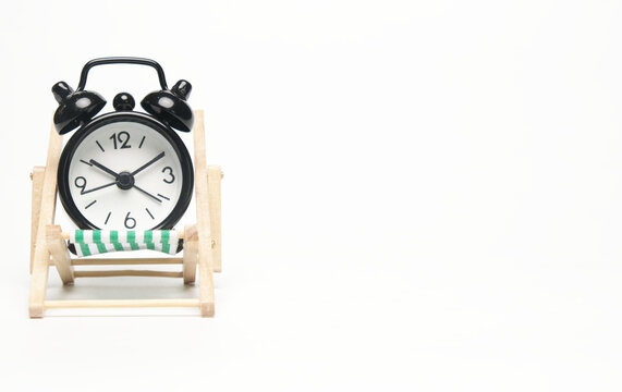 A picture of alarm clock on folding chair on copyspace white background.