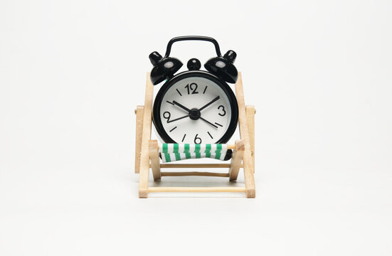 A picture of alarm clock on folding chair on isolated white background. Future plan and work life balance concept.