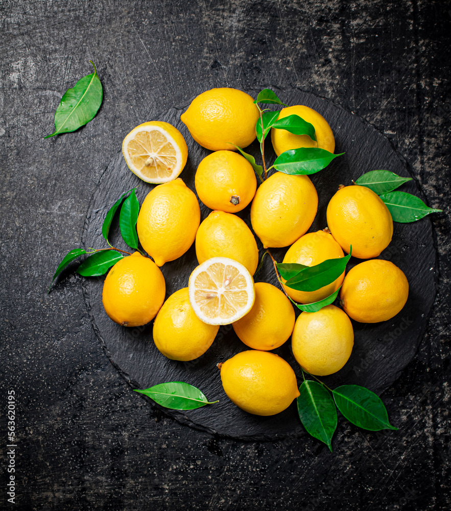 Canvas Prints Juicy lemons with leaves on a stone board. 