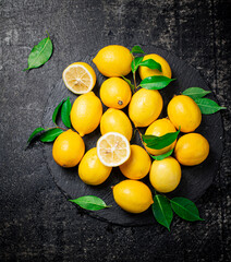 Juicy lemons with leaves on a stone board. 