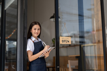 Opening a small business, Happy Asian woman in an apron standing near a bar counter coffee shop, Small business owner, restaurant, barista, cafe, Online, SME, entrepreneur, and seller concept.