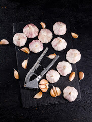 Garlic with a garlic press on a stone board.