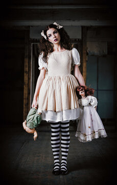 Portrait of weird young girl with dolls in hands