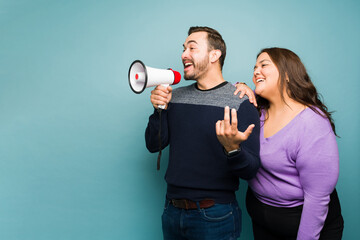 Excited couple giving a message with a megaphone