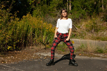 Portrait of woman 50plus in plaid pants and white t-shirt in forest