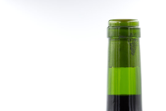 The neck of a green wine bottle with a cork isolated against a white background and with copy space on the left of the image.