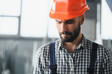Portrait of factory worker in protective equipment in production hall.