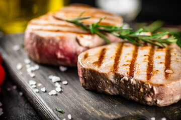 Grilled tuna on a cutting board with a sprig of rosemary. 