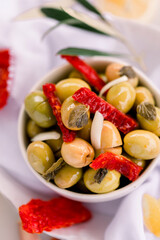 Various olives flavored with spices in white cup and glass jar. Green olives, black olives. Front and top shot on a white background