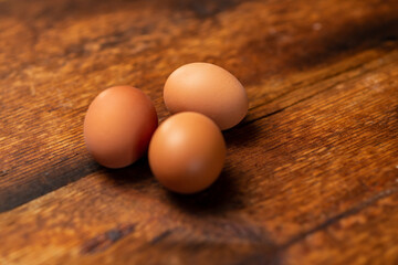 three chicken whole eggs on a wooden surface. Side view.