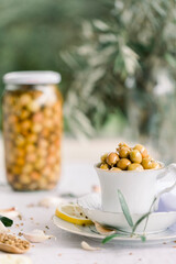 Various olives flavored with spices in white cup and glass jar. Green olives, black olives. Front and top shot on a white background
