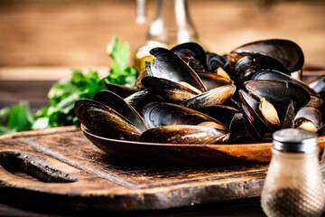 Boiled mussels in a plate on a cutting board with parsley and spices.  © Artem Shadrin