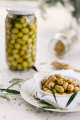 Various olives flavored with spices in white cup and glass jar. Green olives, black olives. Front and top shot on a white background