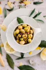 Various olives flavored with spices in white cup and glass jar. Green olives, black olives. Front and top shot on a white background